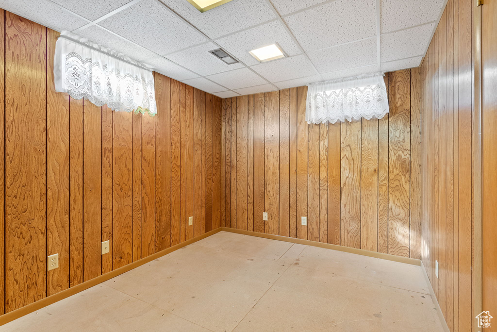 Basement featuring a paneled ceiling and wood walls