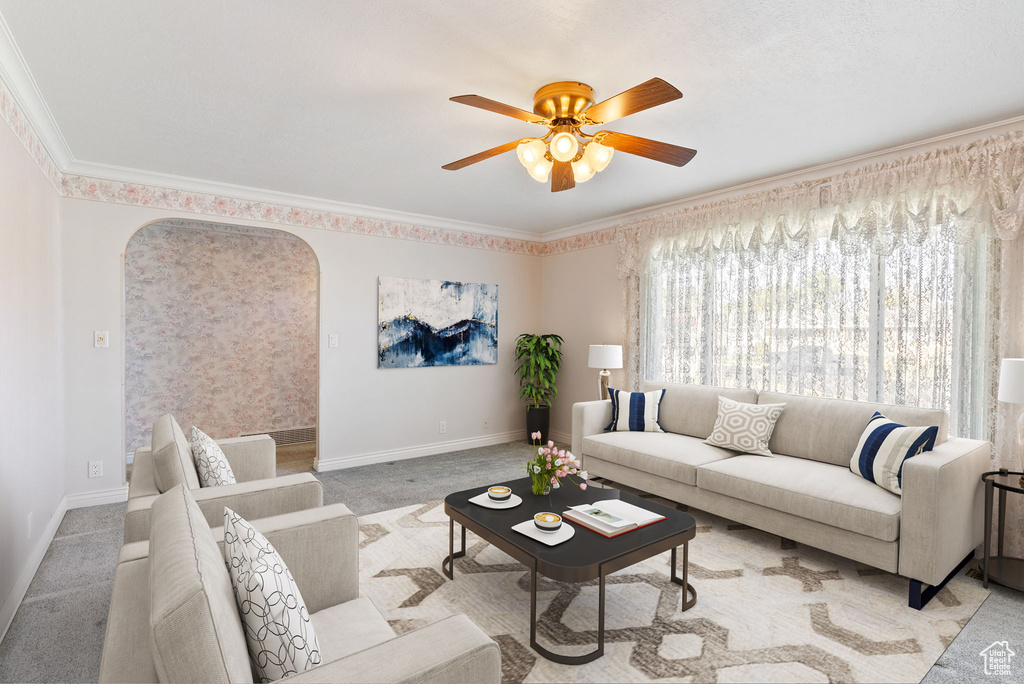 Carpeted living room with ceiling fan and crown molding