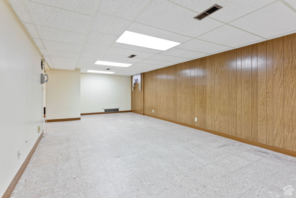 Unfurnished room featuring wood walls and a paneled ceiling