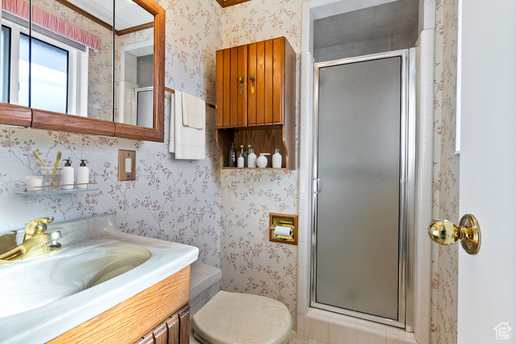 Bathroom featuring ornamental molding, vanity, toilet, and a shower with door