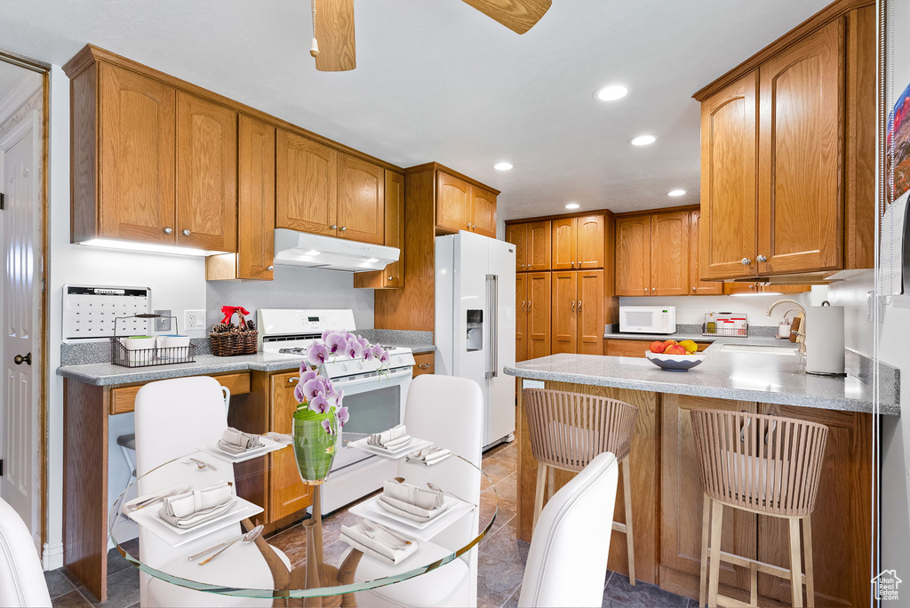 Kitchen with white appliances, sink, tile patterned floors, and a breakfast bar area