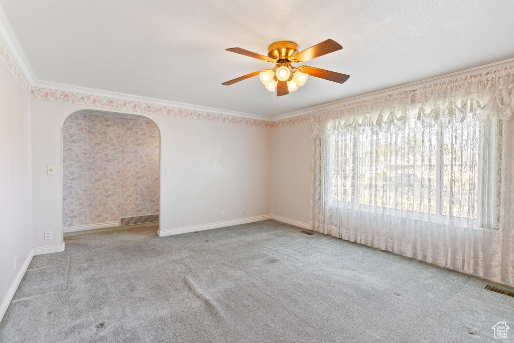 Unfurnished room featuring ceiling fan, light carpet, and ornamental molding