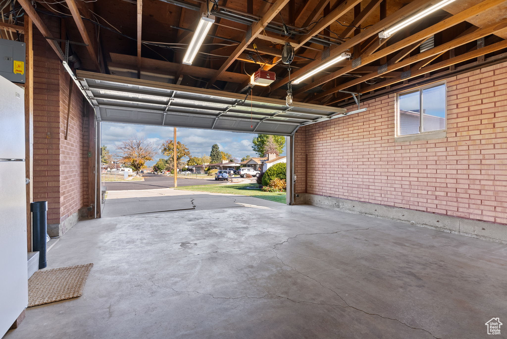 Garage with a garage door opener and white fridge