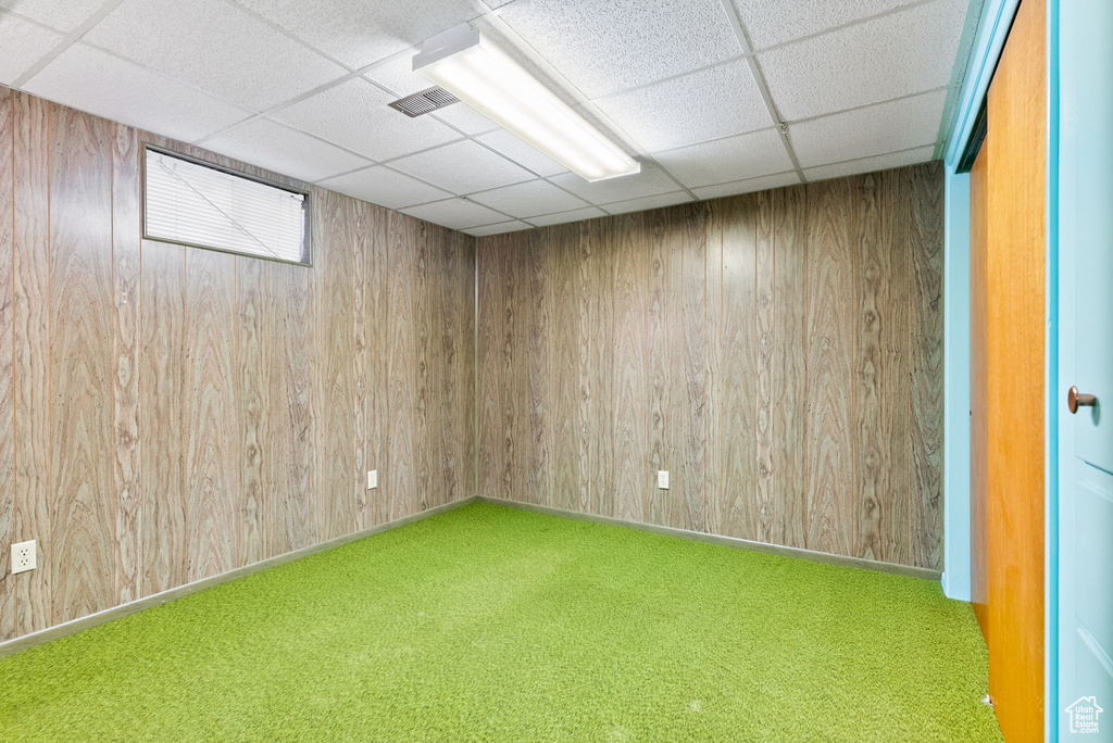 Carpeted spare room with wood walls and a paneled ceiling