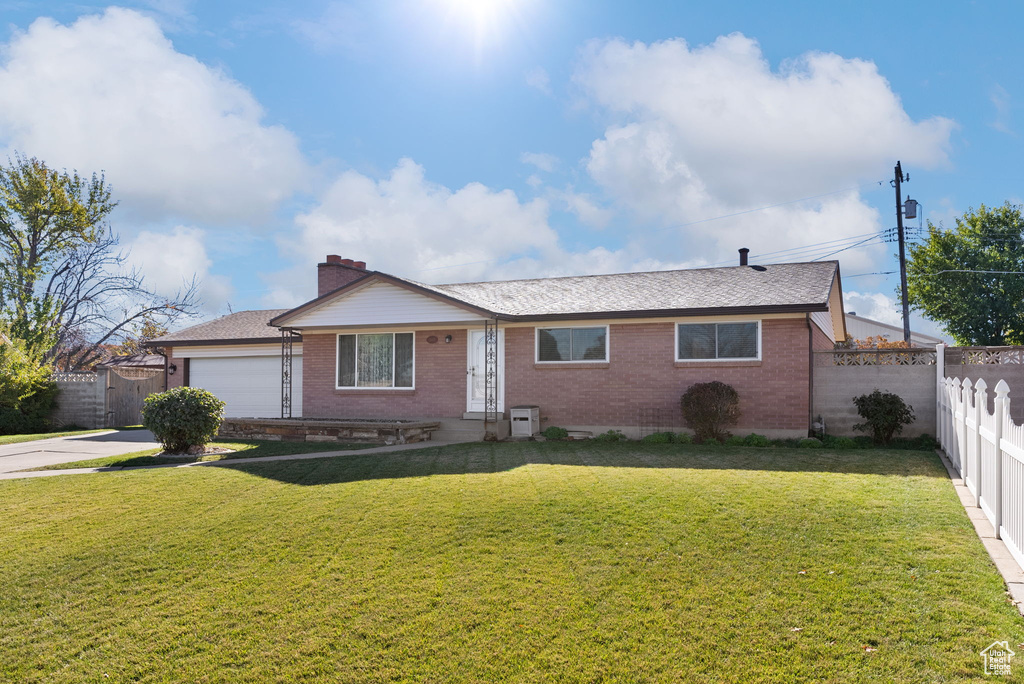 Single story home featuring a garage and a front yard