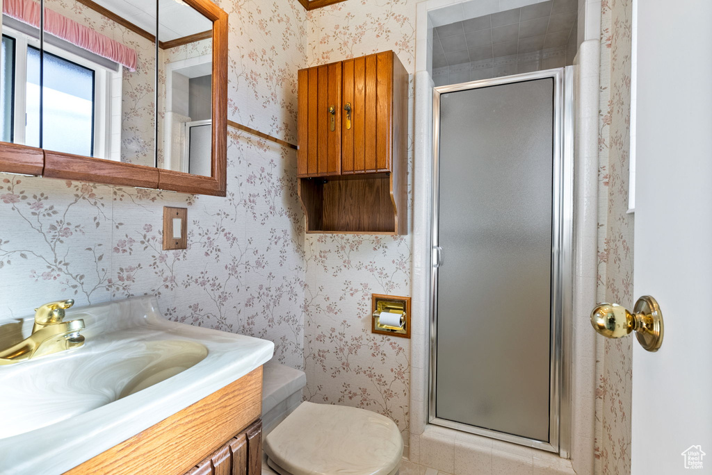 Bathroom featuring a shower with door, vanity, toilet, and crown molding