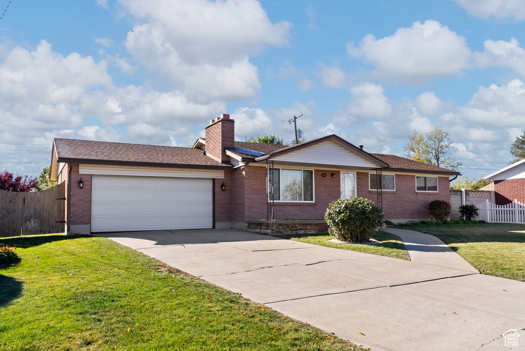 Ranch-style house featuring a garage and a front yard