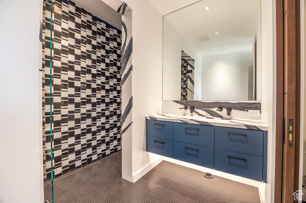 Full bath featuring double vanity and tiled shower