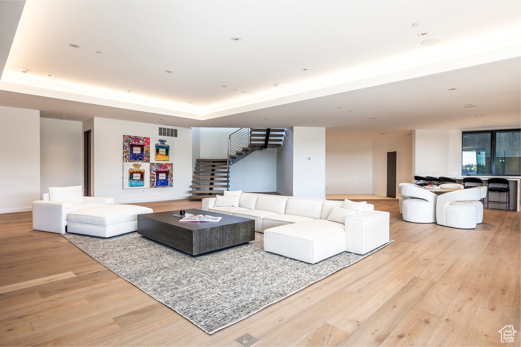 Living area with stairs, wood finished floors, and a raised ceiling
