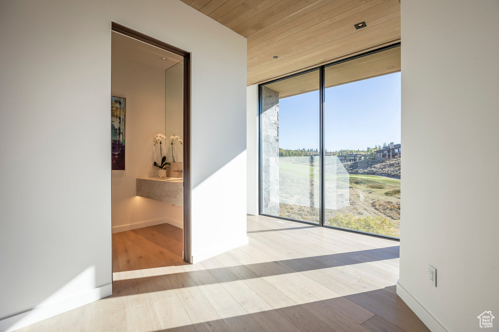 Hall featuring a wall of windows, wood finished floors, wood ceiling, and baseboards