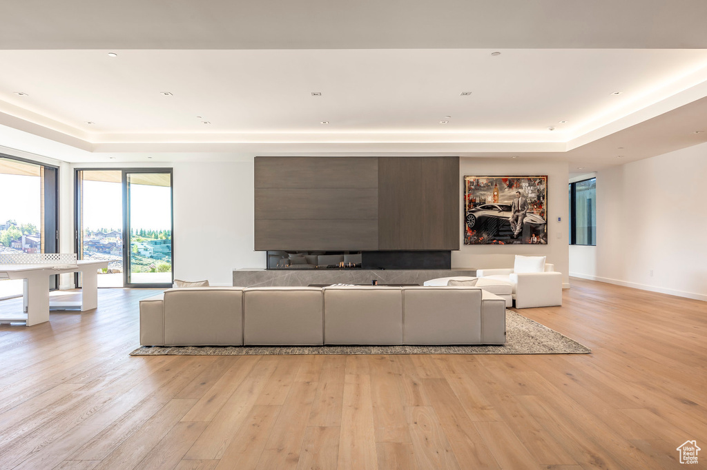 Living area with a tray ceiling and light wood-style flooring