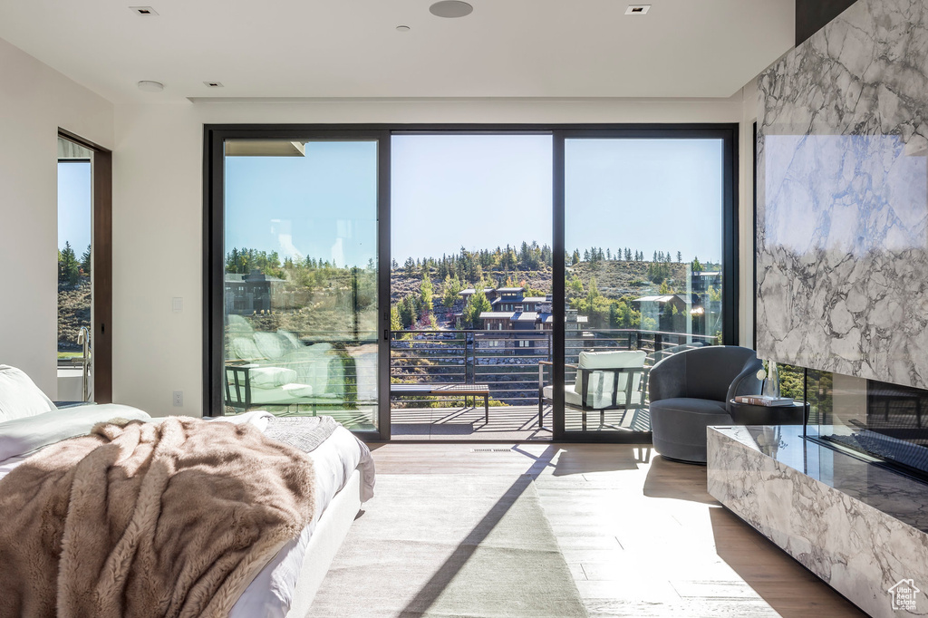 Bedroom with access to outside, a high end fireplace, and wood finished floors