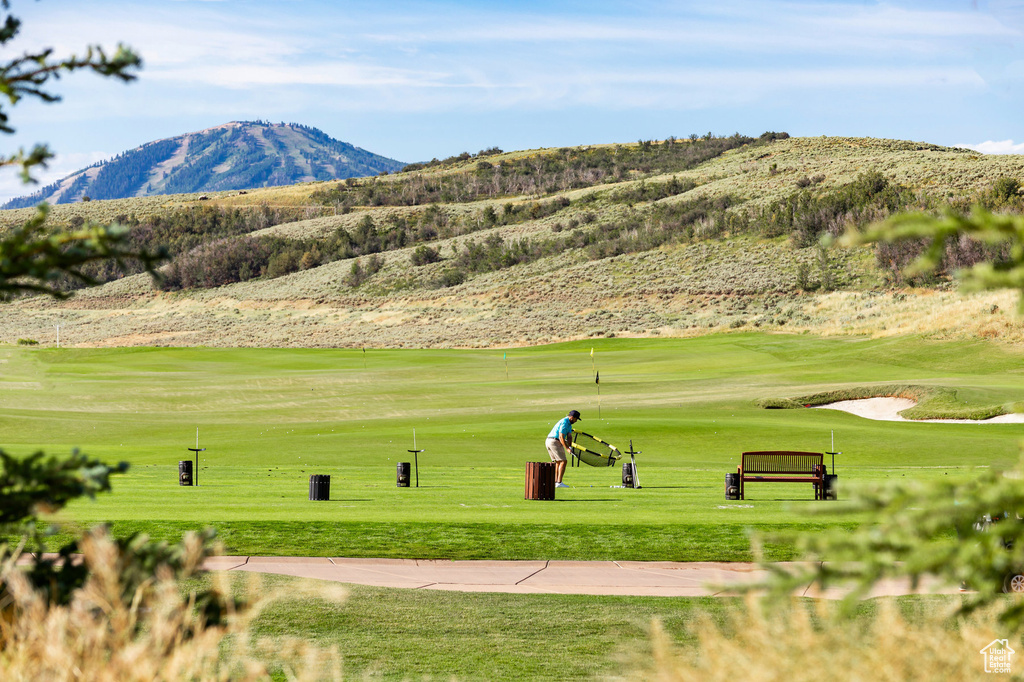 View of home's community featuring a mountain view, view of golf course, and a yard