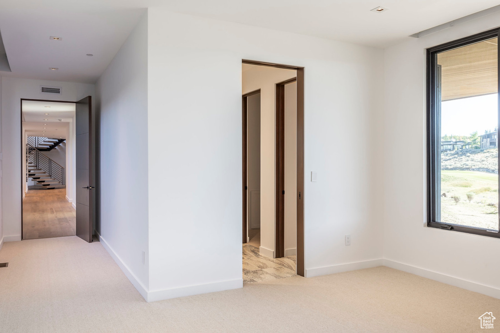 Unfurnished room featuring plenty of natural light, light colored carpet, and baseboards