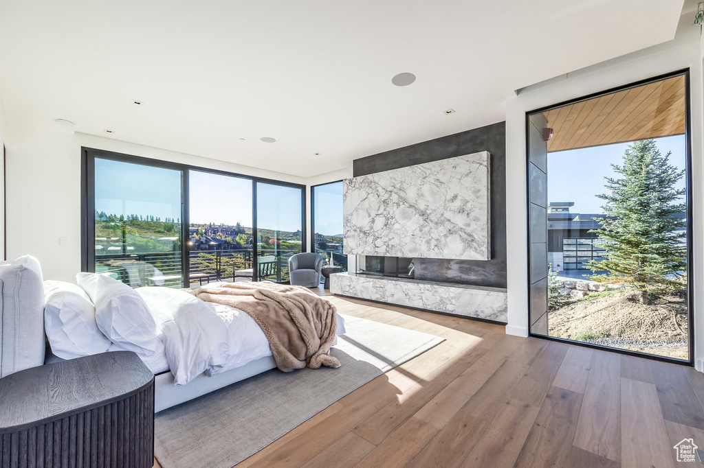 Bedroom with floor to ceiling windows, multiple windows, wood finished floors, and access to outside