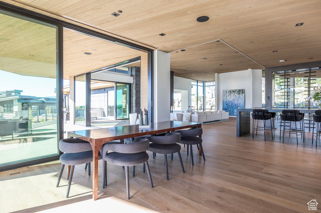 Dining room featuring wood ceiling, plenty of natural light, wood finished floors, and a wall of windows