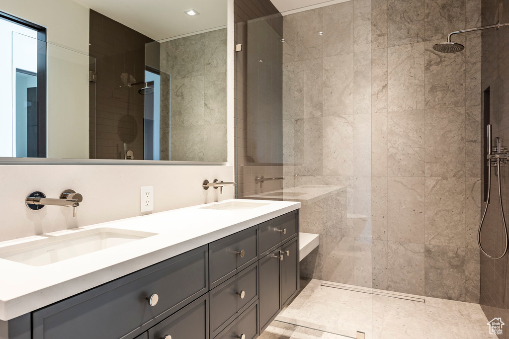 Bathroom with a walk in shower, double vanity, and tile walls