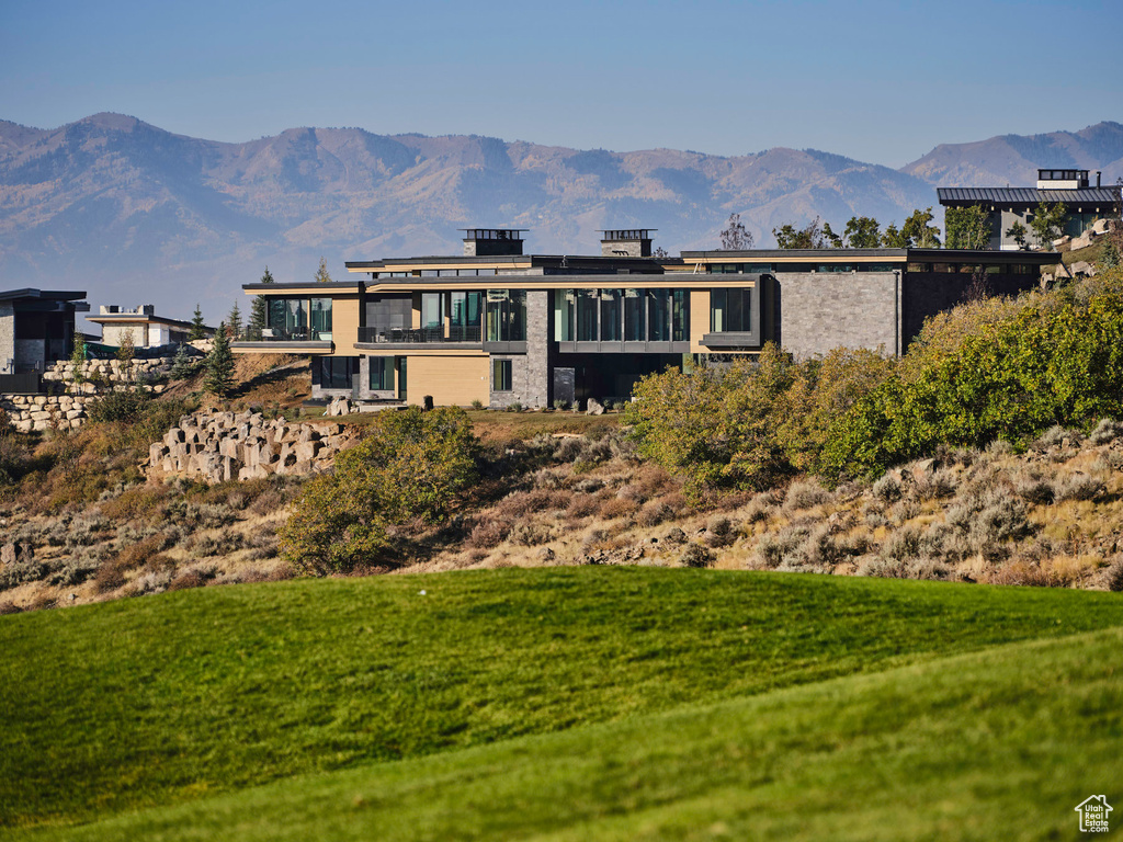 Rear view of property with a mountain view and a yard