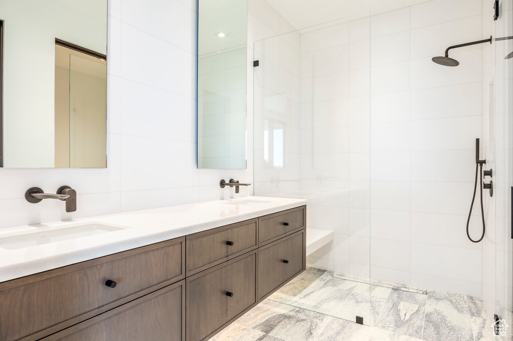 Full bath featuring tile walls, a walk in shower, and double vanity