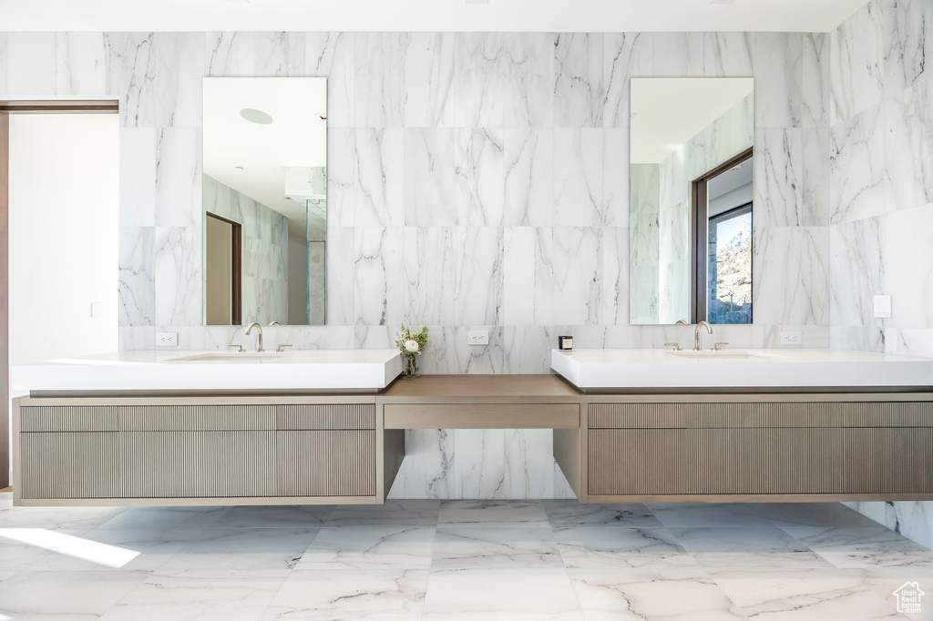 Full bathroom with vanity and tile walls