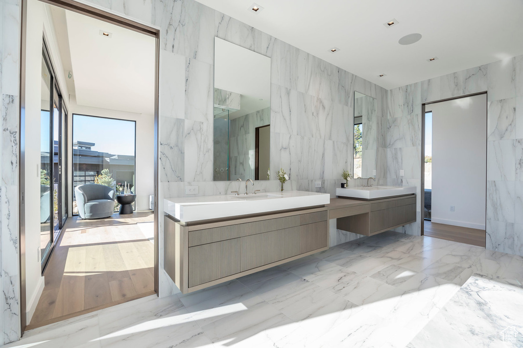 Bathroom featuring plenty of natural light, vanity, and tile walls