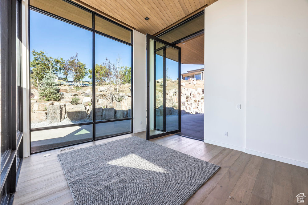 Unfurnished room featuring floor to ceiling windows, wood ceiling, wood finished floors, and baseboards