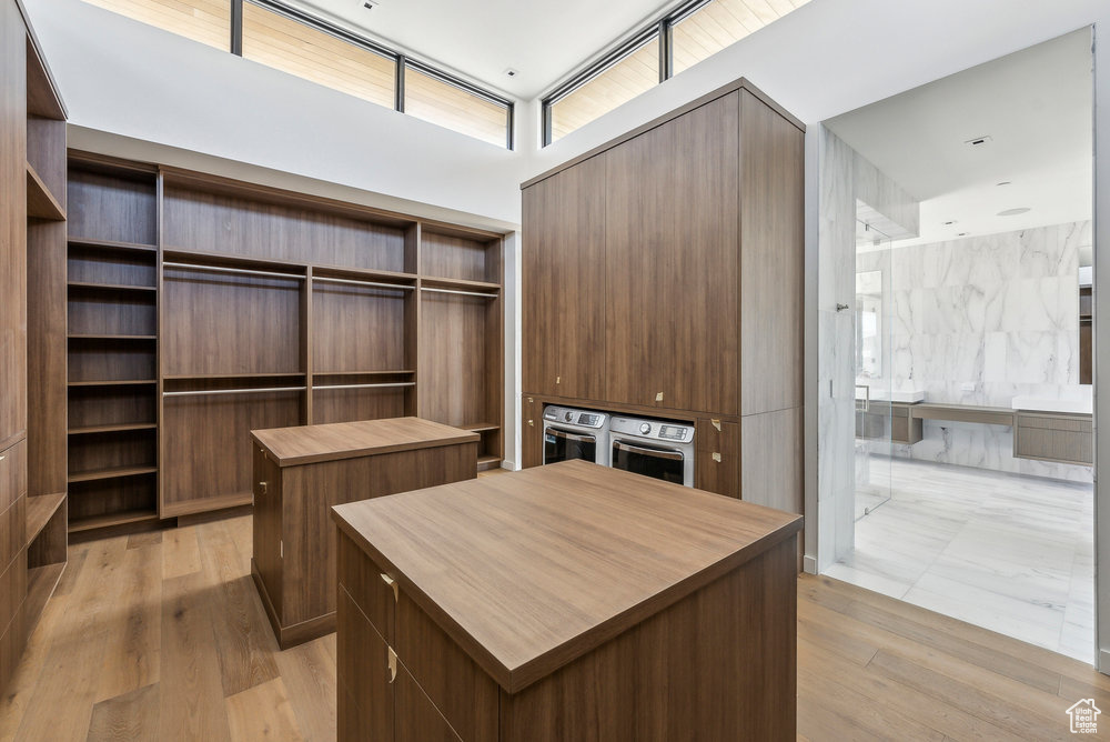 Walk in closet featuring light wood-style flooring and a high ceiling