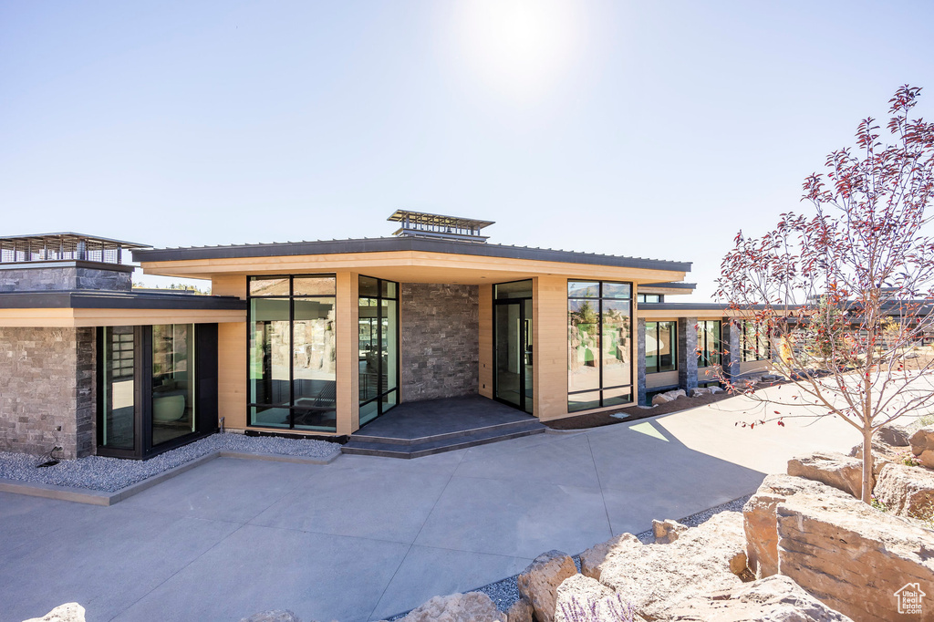 Rear view of house with a patio and stone siding