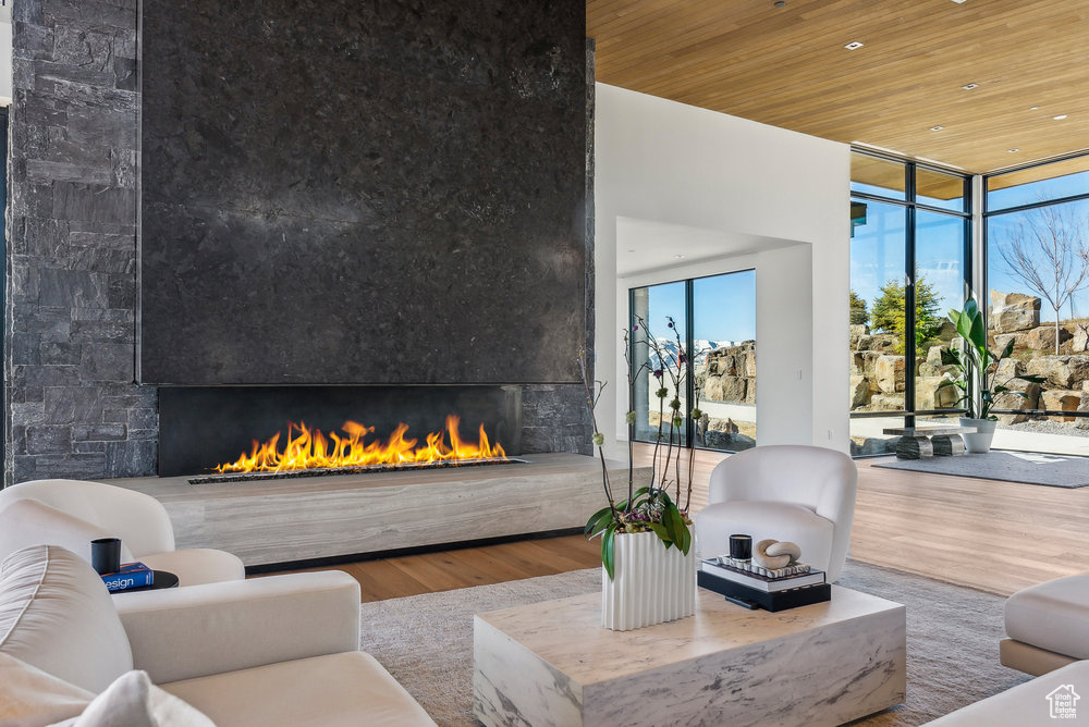 Living area with a large fireplace, a wall of windows, wood ceiling, wood finished floors, and recessed lighting