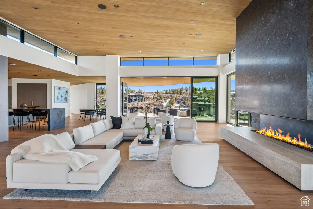 Living room with wood ceiling, wood finished floors, a fireplace, a high ceiling, and recessed lighting