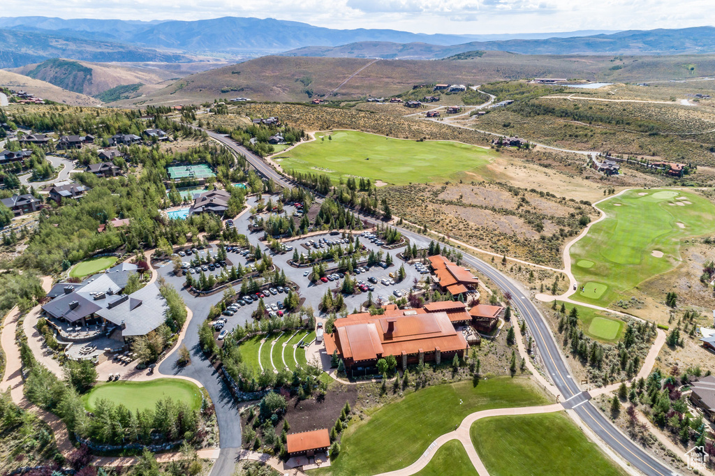 Aerial view of property and surrounding area featuring mountains and a local golf course