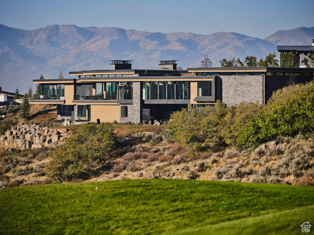 Back of property with a mountain view and a yard