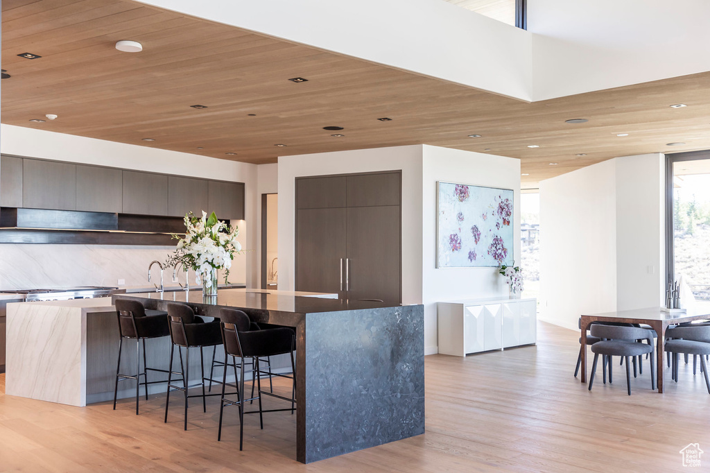 Kitchen featuring modern cabinets, a spacious island, a breakfast bar, light wood finished floors, and recessed lighting