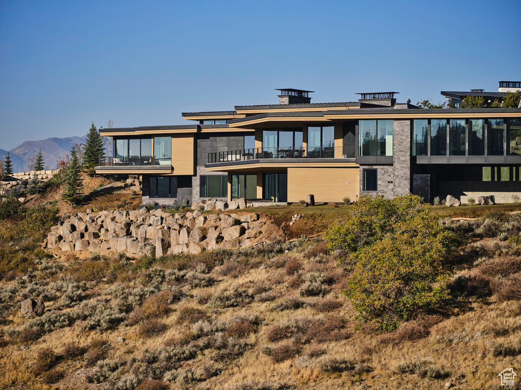Back of house with a mountain view and a balcony
