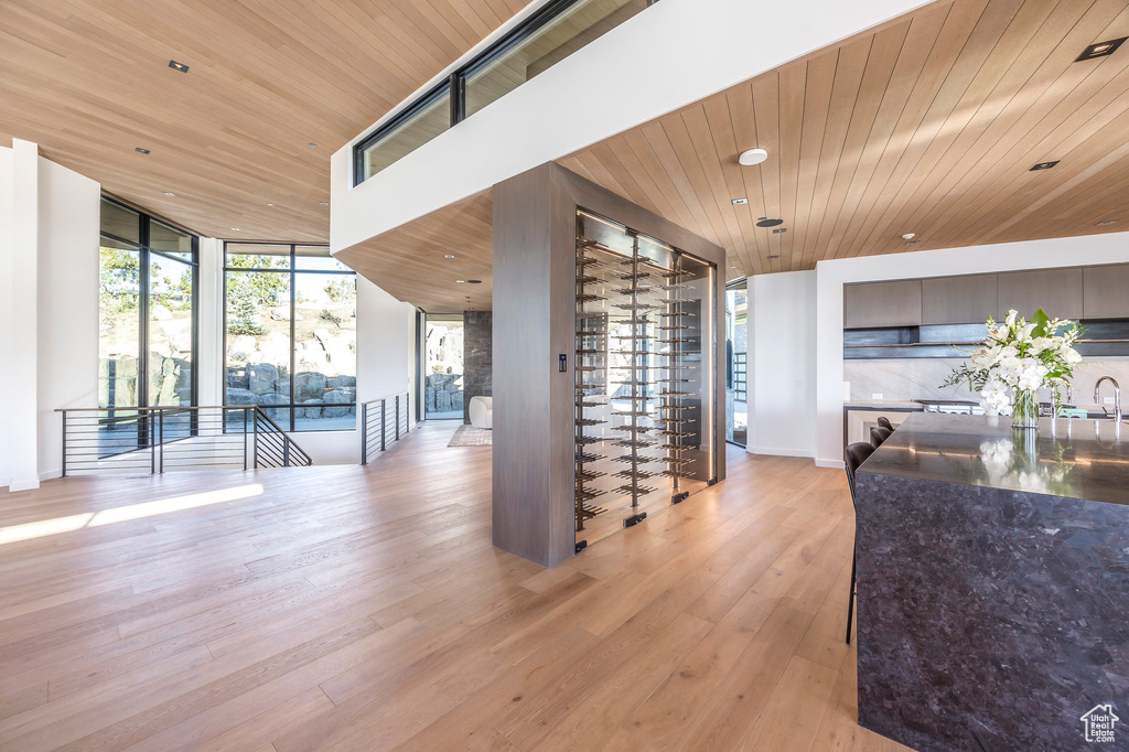Living area featuring wood ceiling, floor to ceiling windows, light wood finished floors, and baseboards