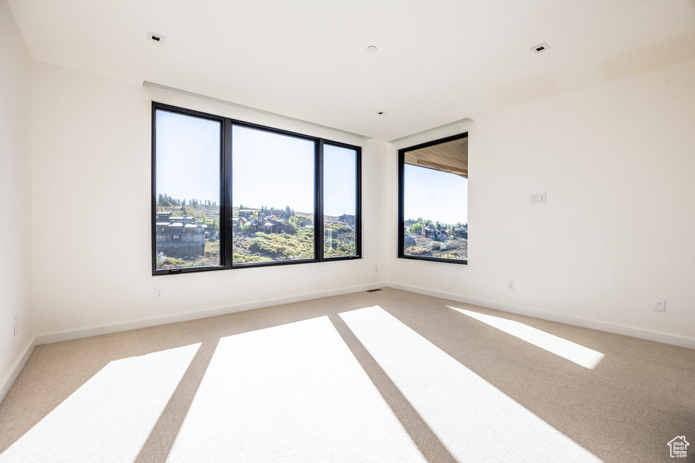 Empty room featuring light colored carpet and baseboards