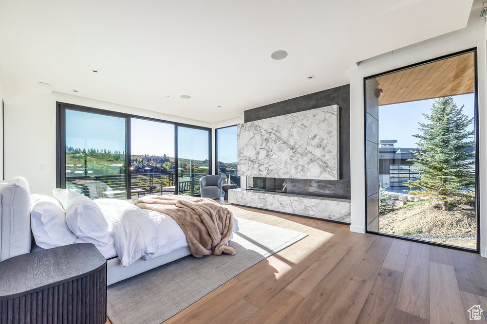 Bedroom with floor to ceiling windows, wood finished floors, and access to exterior