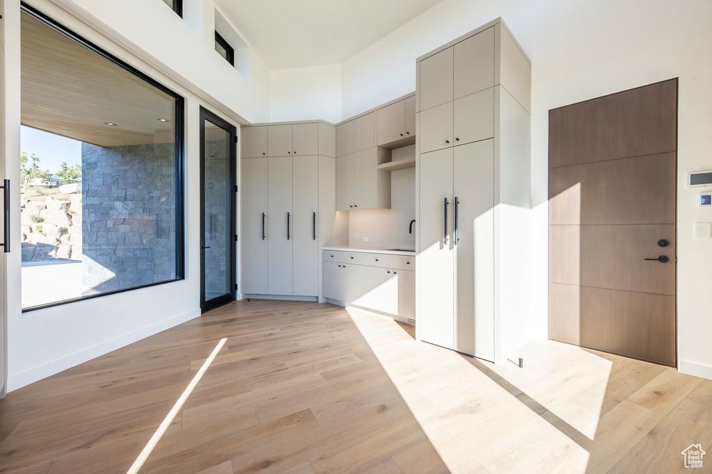 Kitchen with gray cabinets, light wood-style floors, open shelves, baseboards, and light countertops