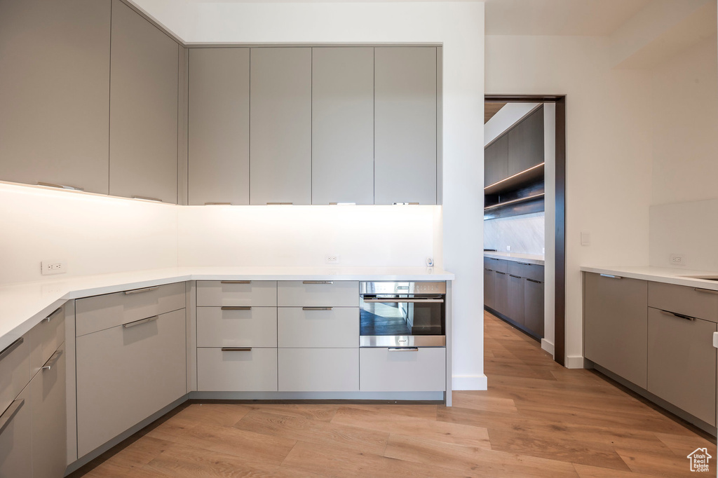 Kitchen featuring stainless steel oven, gray cabinetry, modern cabinets, and light wood-style floors
