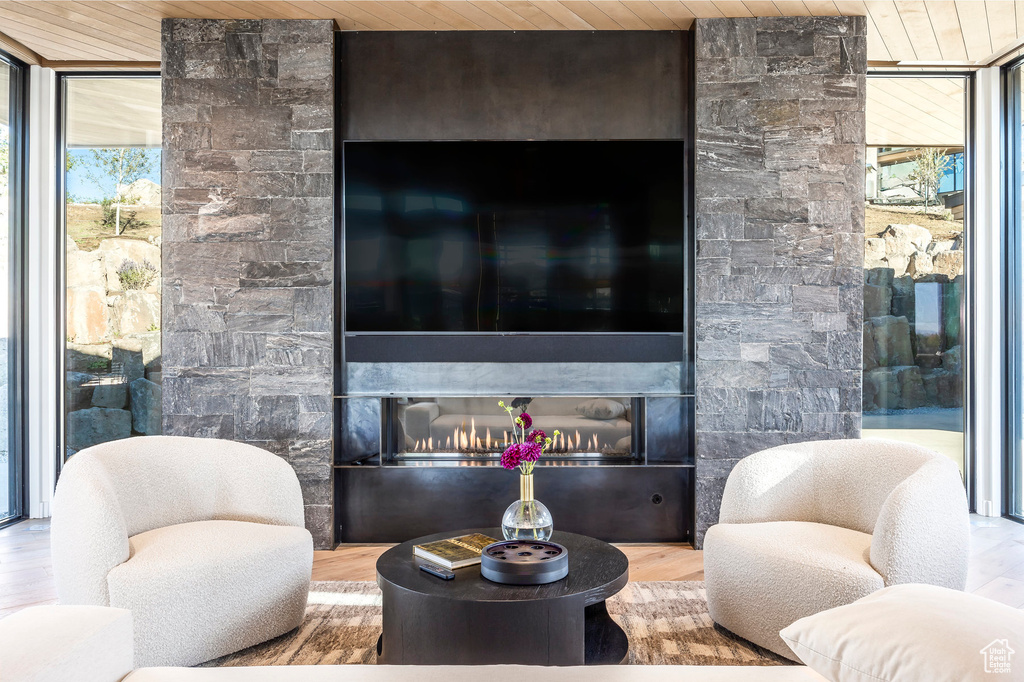 Living area featuring wood ceiling, a lit fireplace, wood finished floors, and floor to ceiling windows