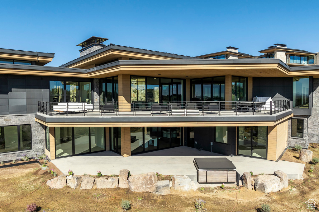 Back of property featuring a balcony and a patio area