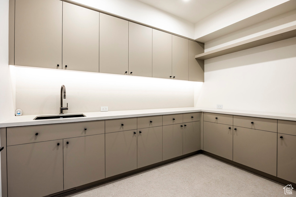 Kitchen featuring a sink, gray cabinets, light countertops, and open shelves