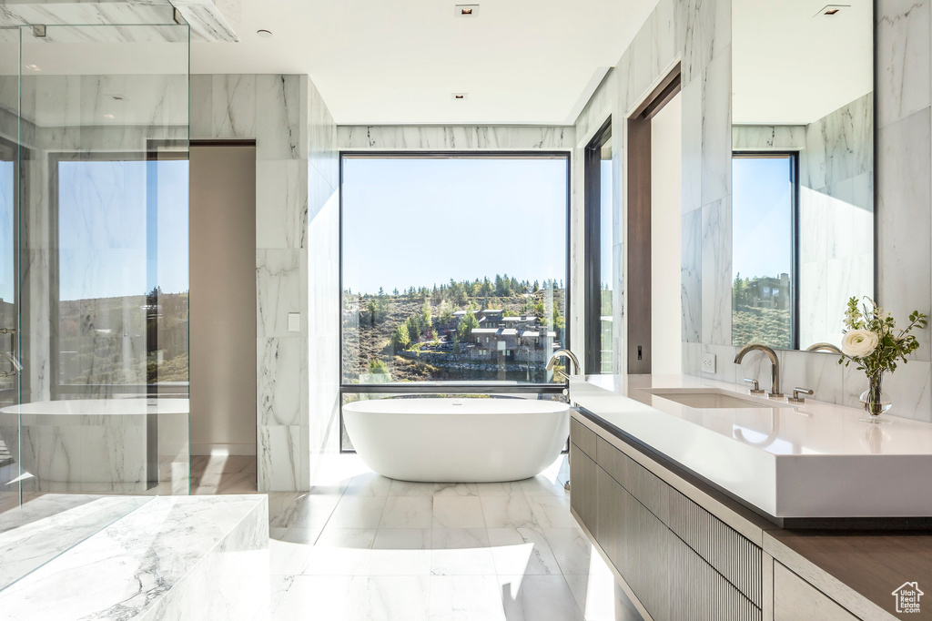 Full bath featuring a freestanding tub, marble tiled flooring, and vanity