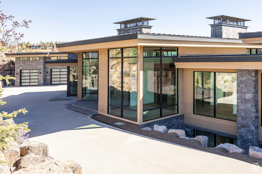 Property entrance featuring concrete driveway and a chimney