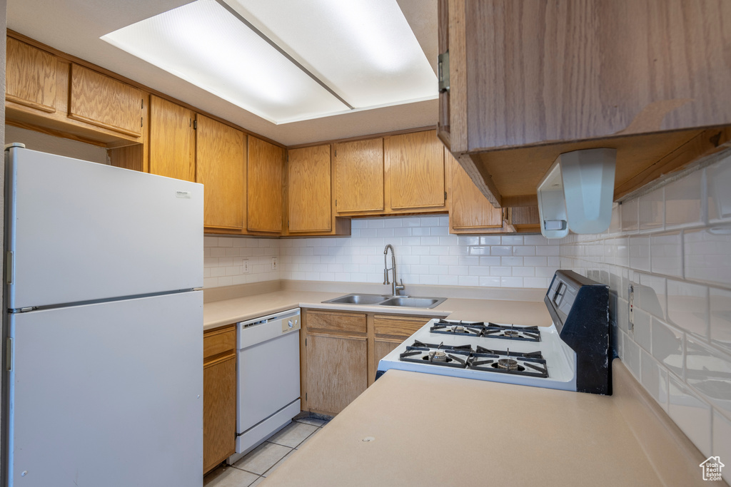 Kitchen with tasteful backsplash, white appliances, and sink