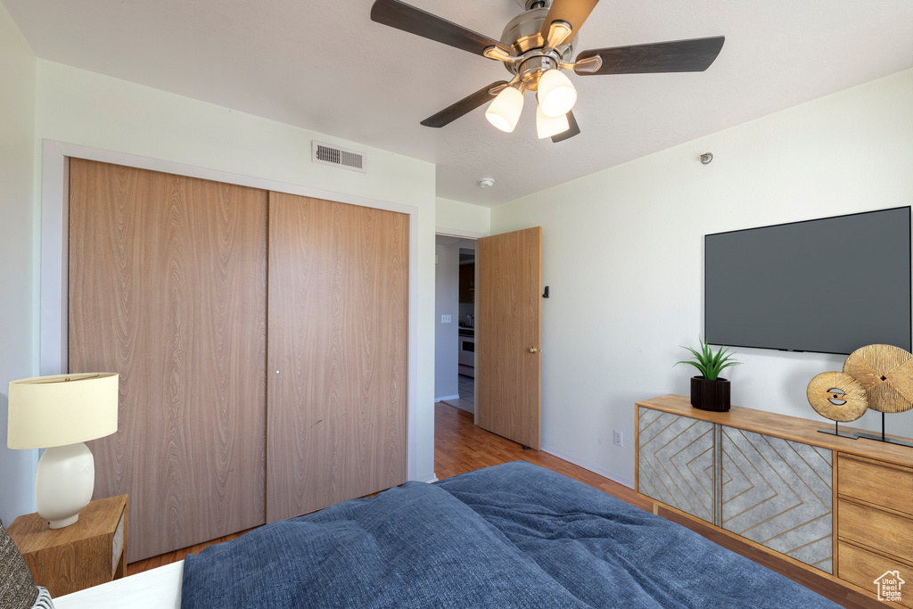 Bedroom with ceiling fan, a closet, and light hardwood / wood-style flooring