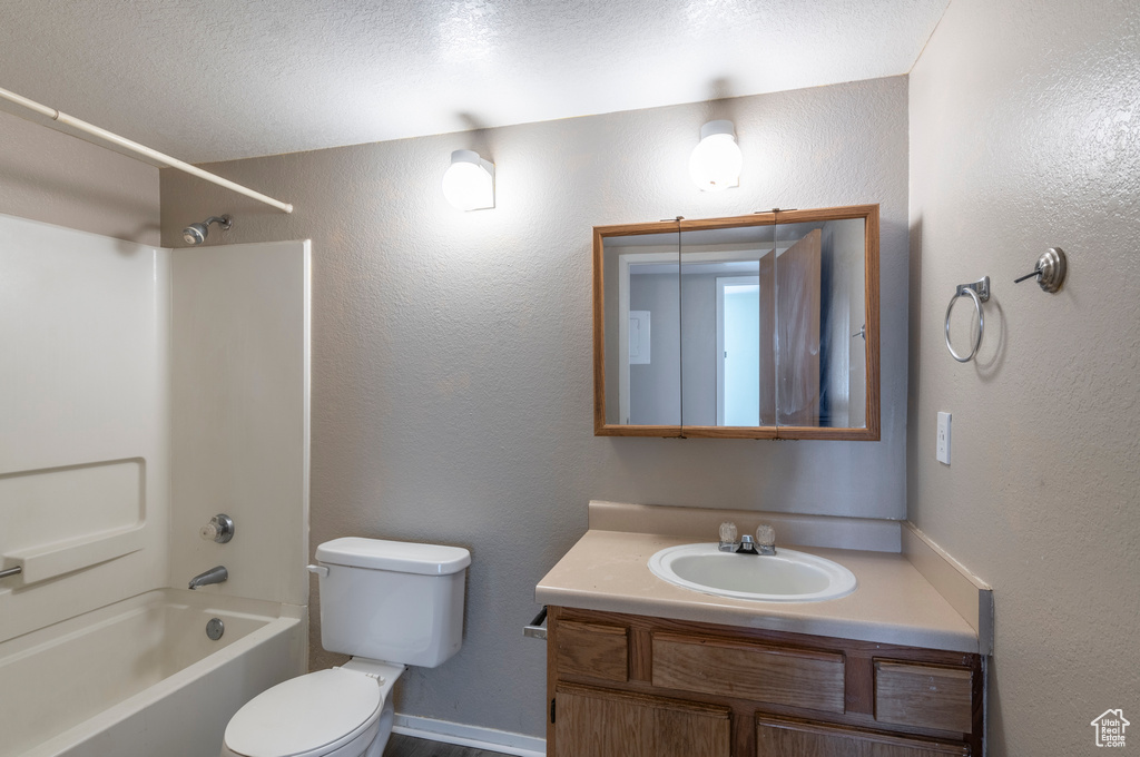 Full bathroom with toilet, bathtub / shower combination, vanity, and a textured ceiling