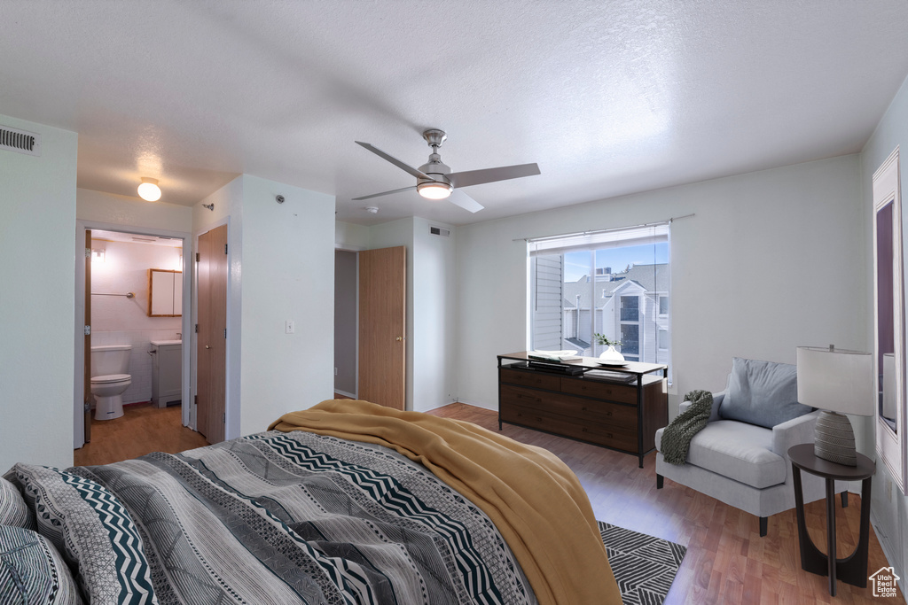 Bedroom with ceiling fan, connected bathroom, and light hardwood / wood-style flooring