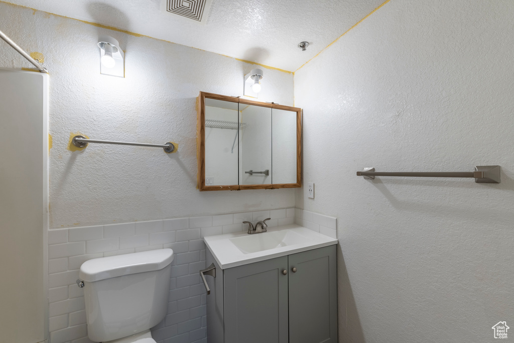 Bathroom with tile walls, vanity, a textured ceiling, and toilet