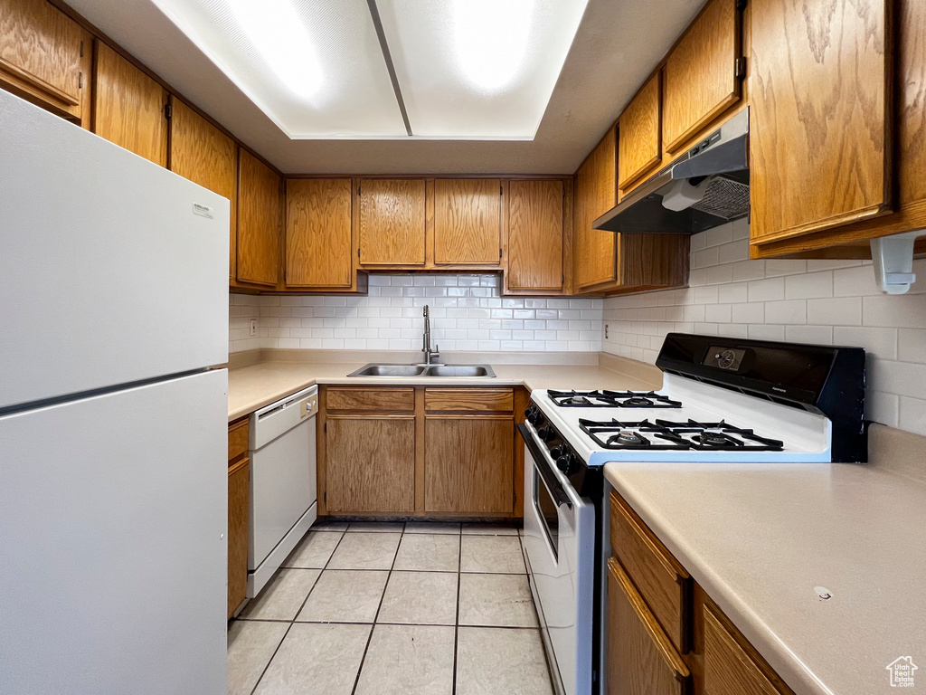 Kitchen with backsplash, white appliances, sink, and light tile patterned floors